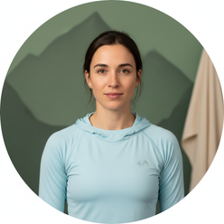 Circular portrait of rock climber Sasha DiGiulian, chest up, with a determined expression against a softly blurred mountain b